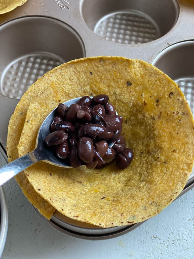 process shot of adding black beans to tortillas