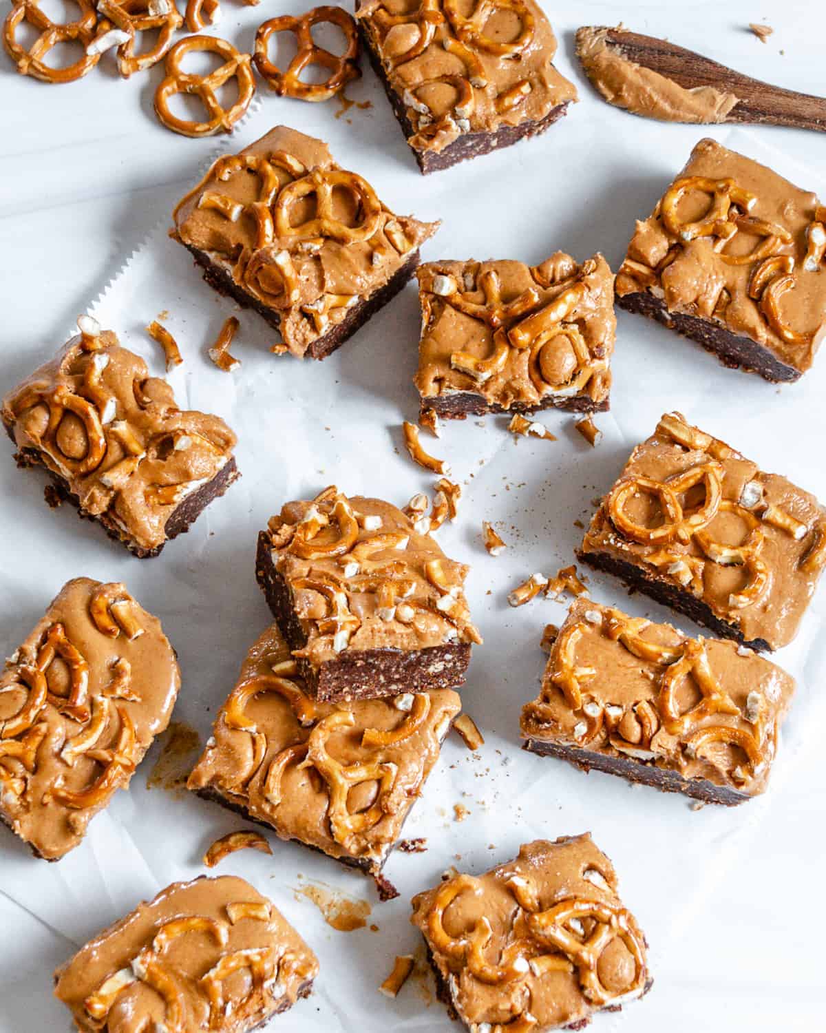 several finished Easy Chocolate Peanut Butter Pretzel Bars cut up into bite size squares against a white background