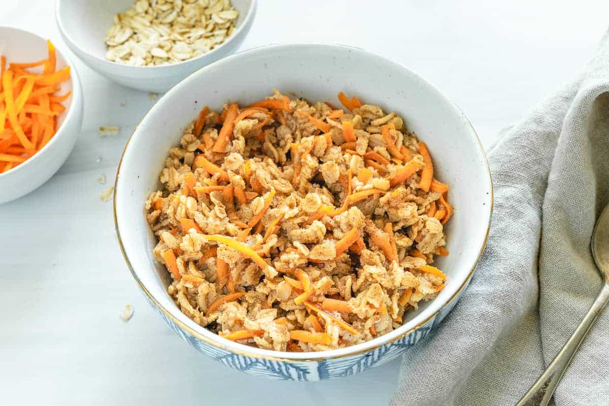 cooked carrot cake oatmeal in a white bowl against a white surface