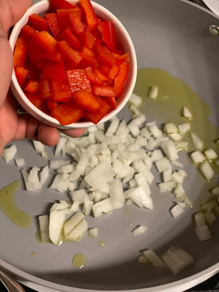 process shot of adding tomatoes to a pan