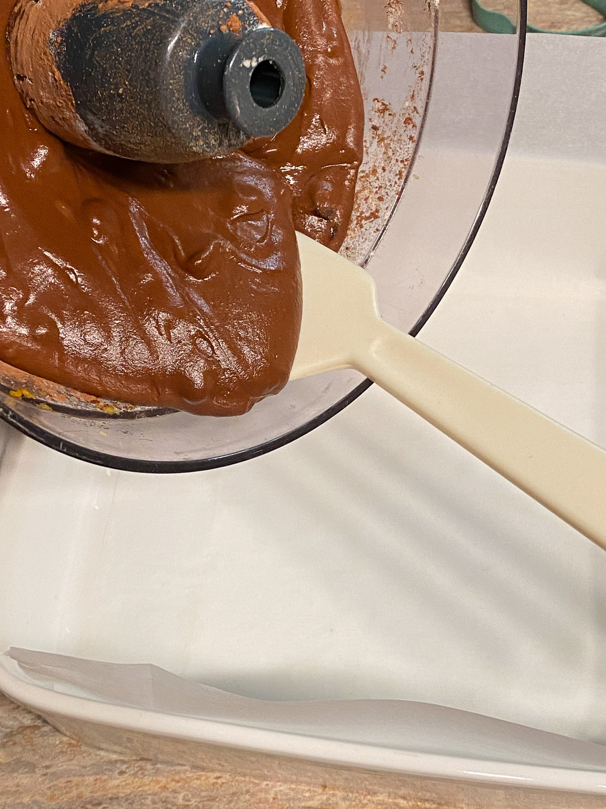 process of pouring the sweet potato brownie mixture into white baking tray