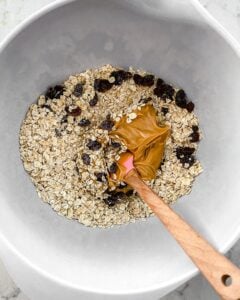 process of mixing ingredients of Oatmeal Raisin Protein Balls in a white bowl