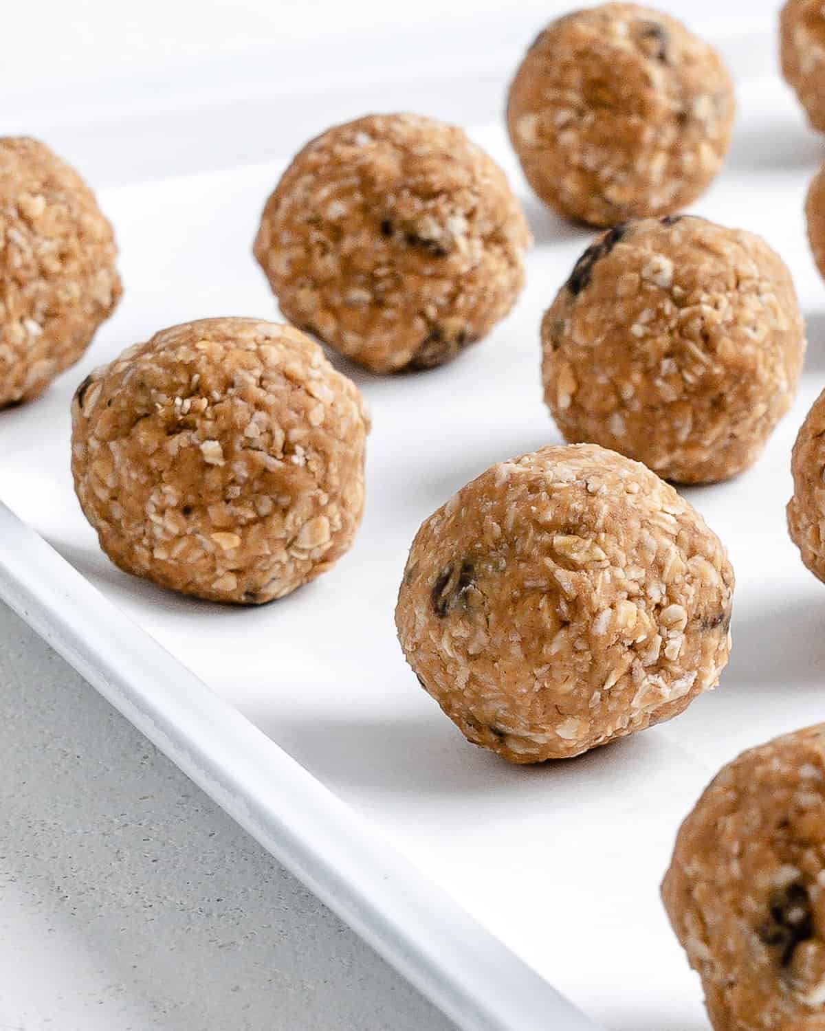Oatmeal Raisin Protein Balls into balls on a white tray surface