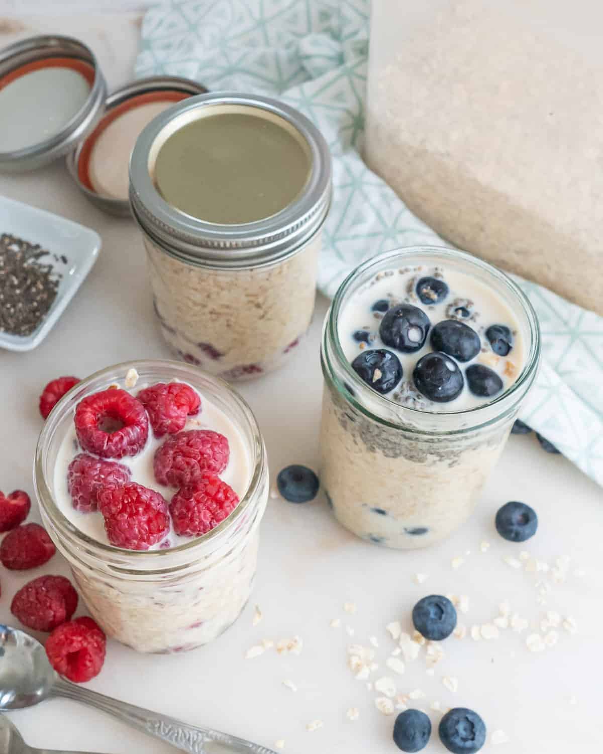 completed overnight oats in three separate jars with three different varieties against a white background and 