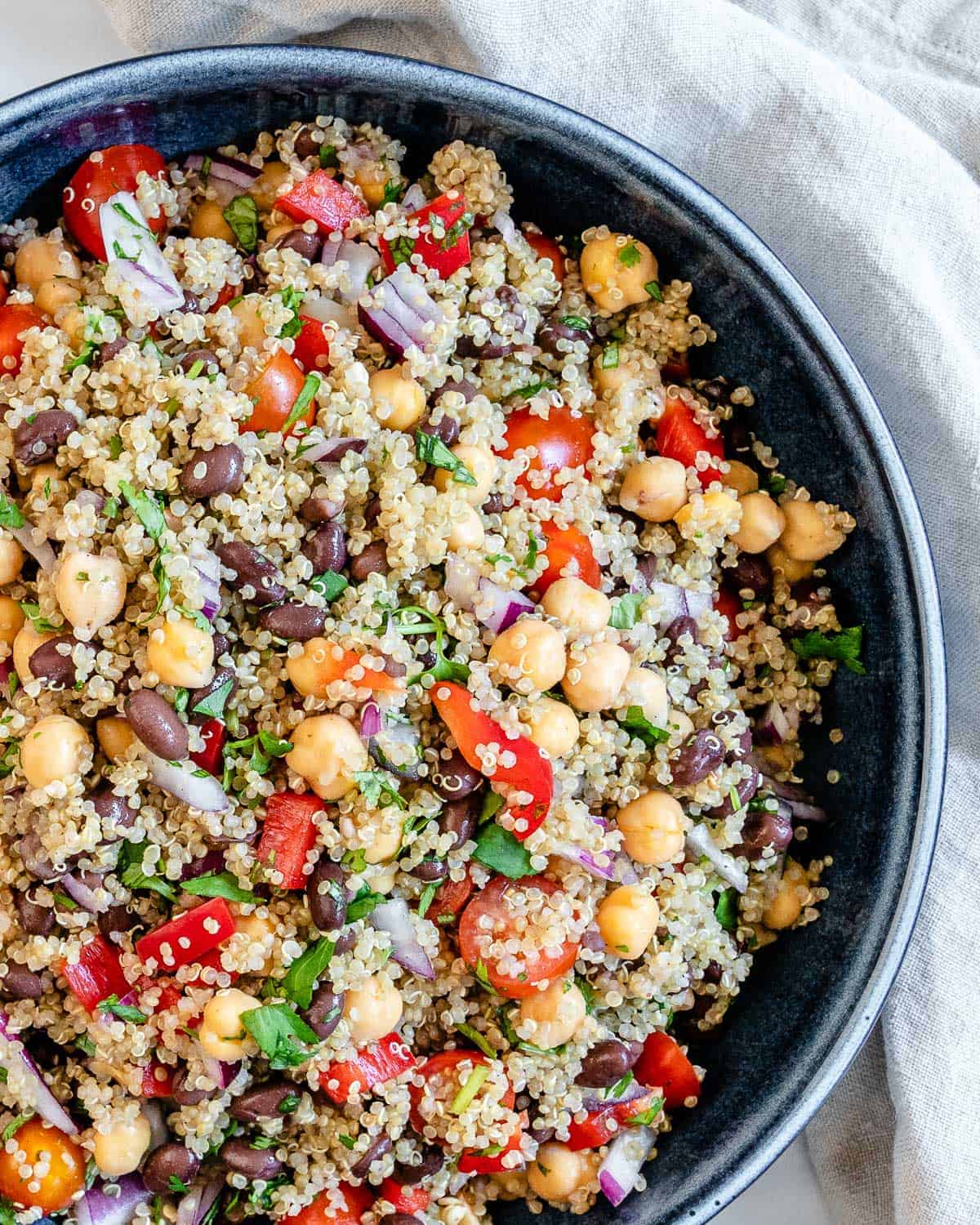 completed Fresh Quinoa Salad in a blue bowl against a white background