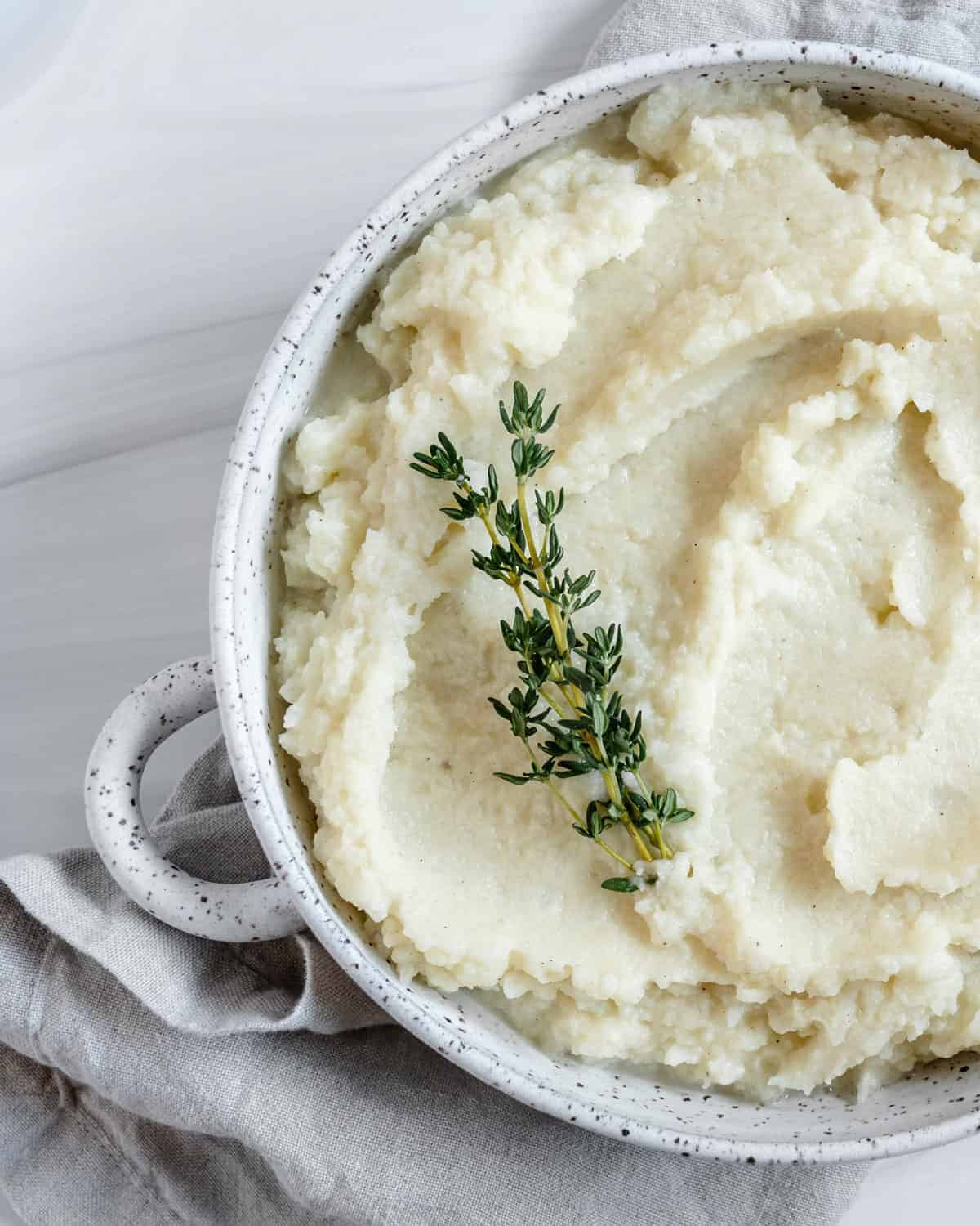 completed mashed cauliflower in a white dish against white background