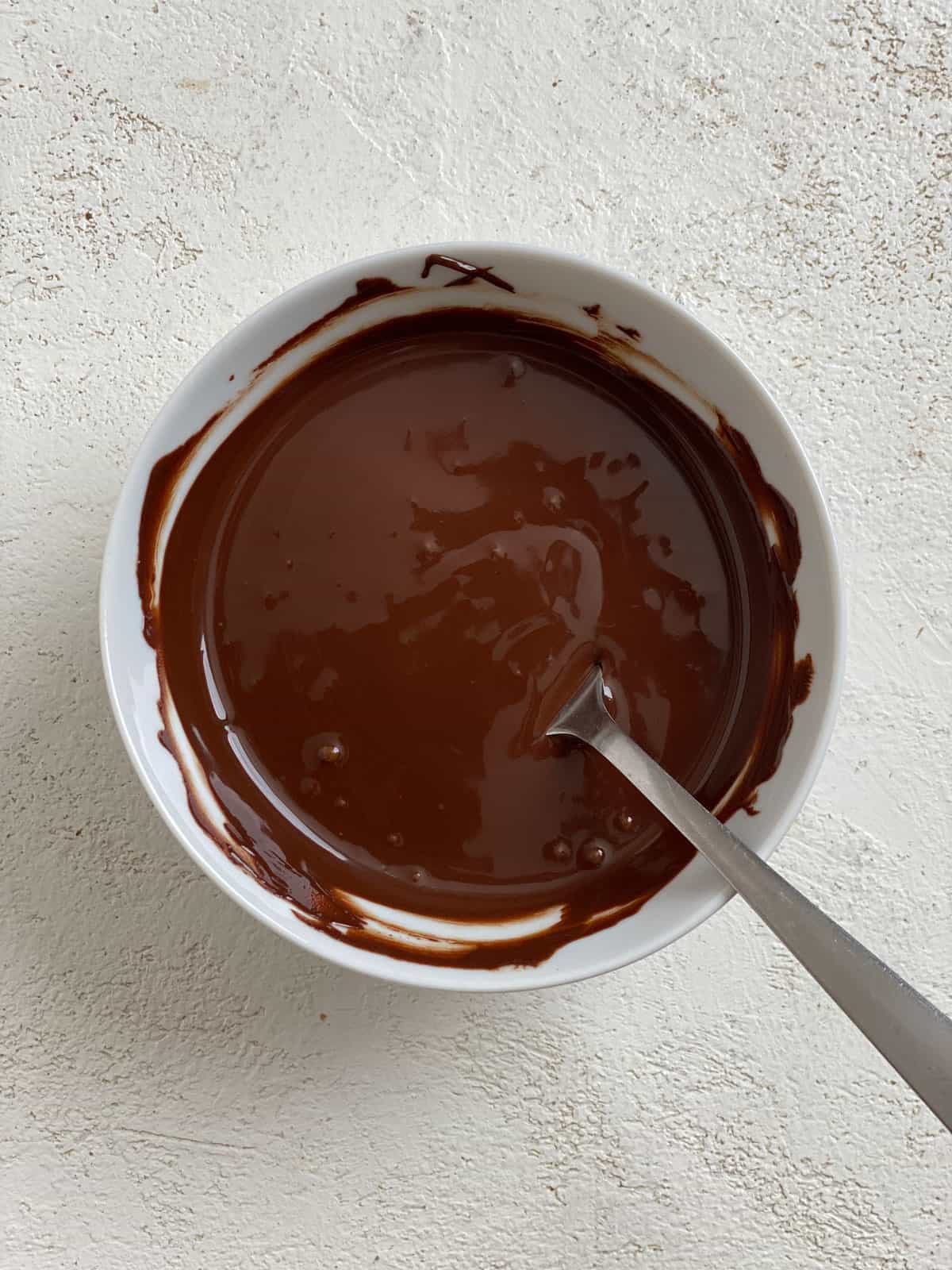 post melted vegan chocolate chips in a bowl against a white surface