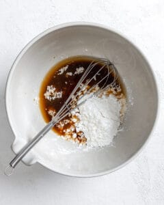 process of adding ingredients to form sauce for breaded tofu strips in a white bowl