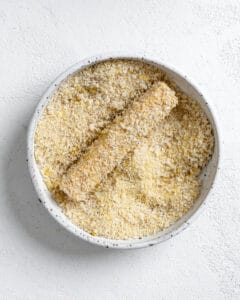 adding tofu strip to breaded ingredients in a white bowl