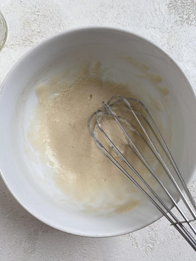 process shot of mixing icing ingredients in bowl with whisk