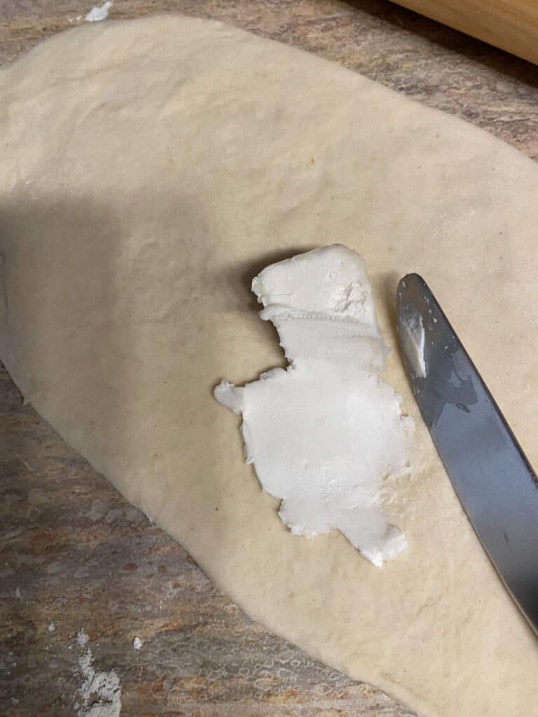 process s،t s،wing the spreading of vegan margarine on dough