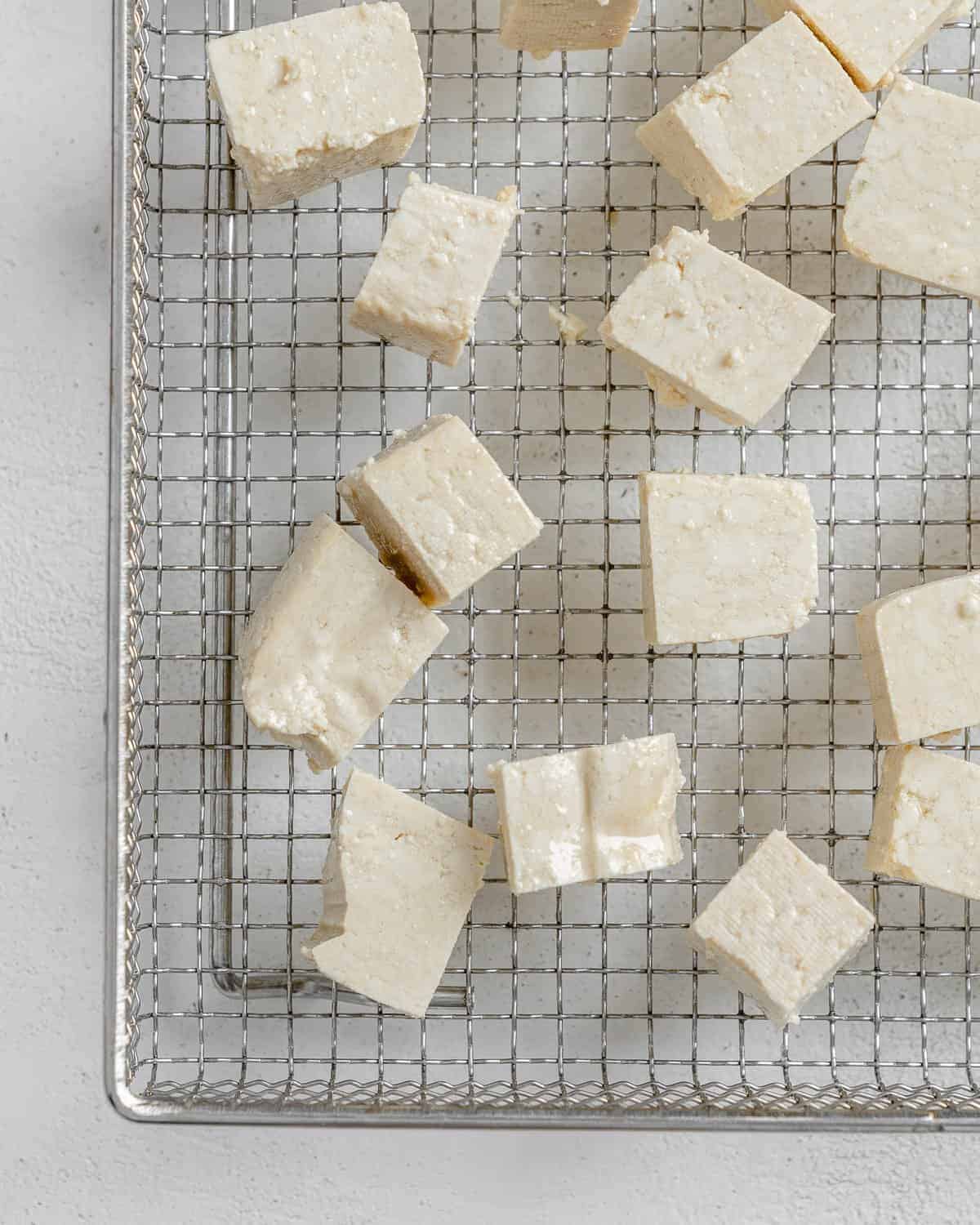 process shot of tofu squares on wire rack against a white surface