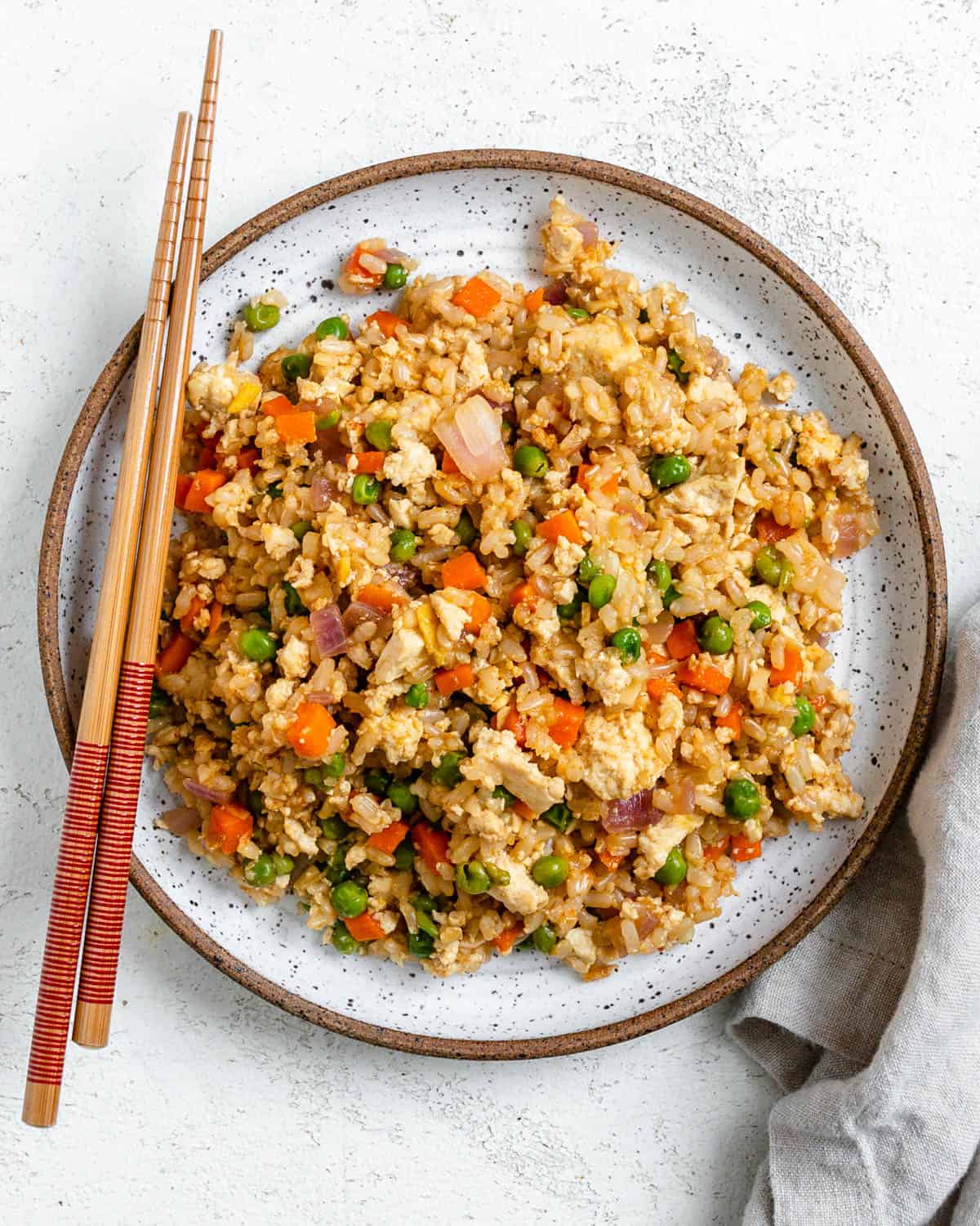completed Easy Vegetable Brown Fried Rice plated on a white plate against a light background alongside chopsticks