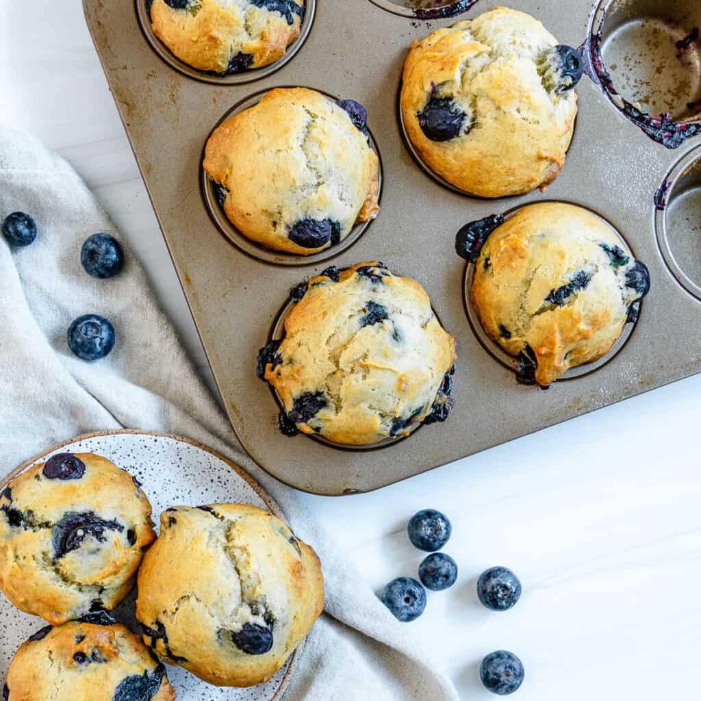 completed blueberry banana muffins in tin and plated against white surface