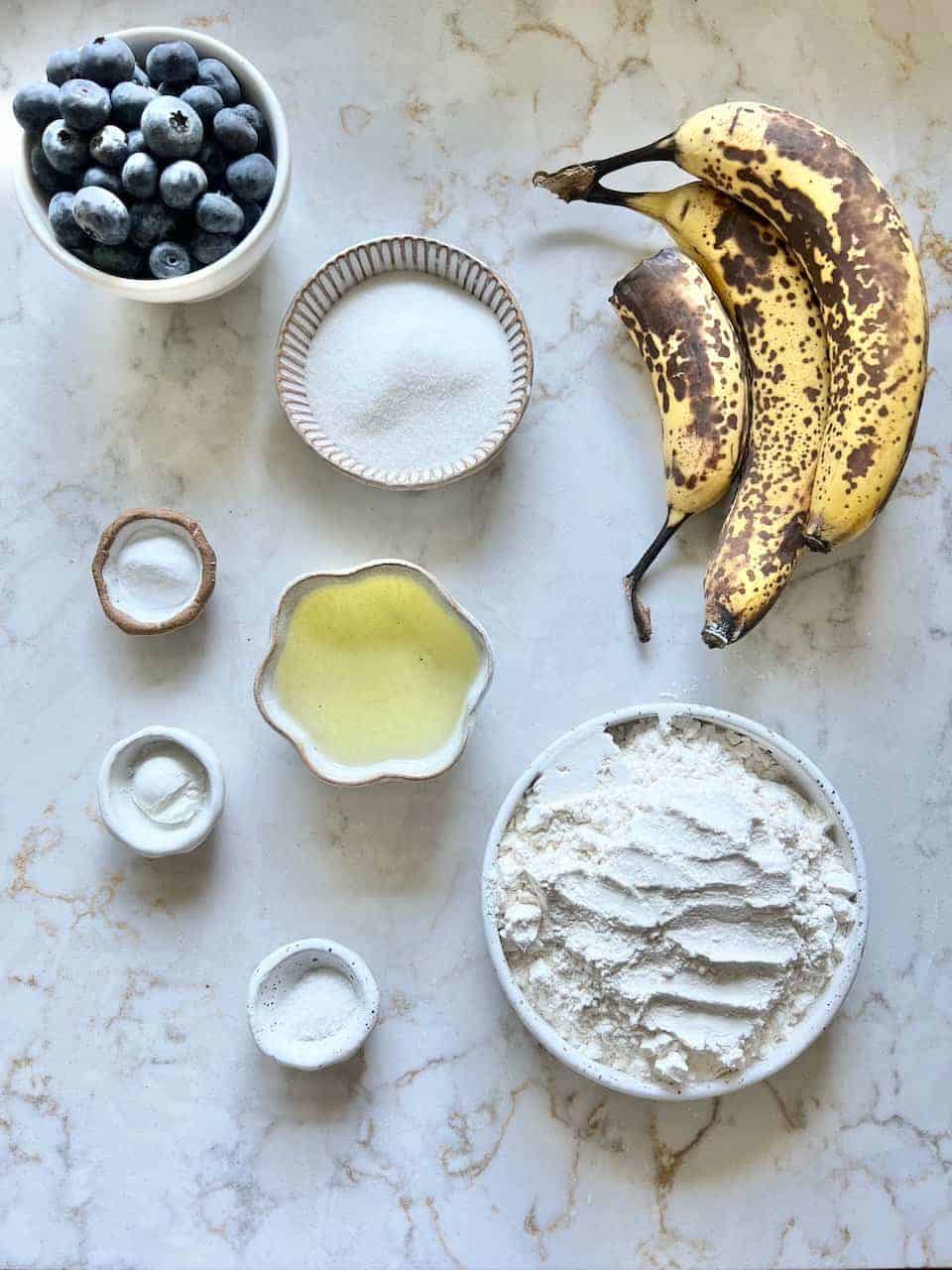 measured out ingredients for Easy Blueberry Banana Muffins against a white surface