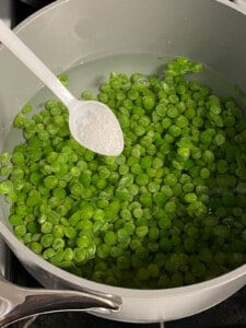 process of adding salt to peas in a pot