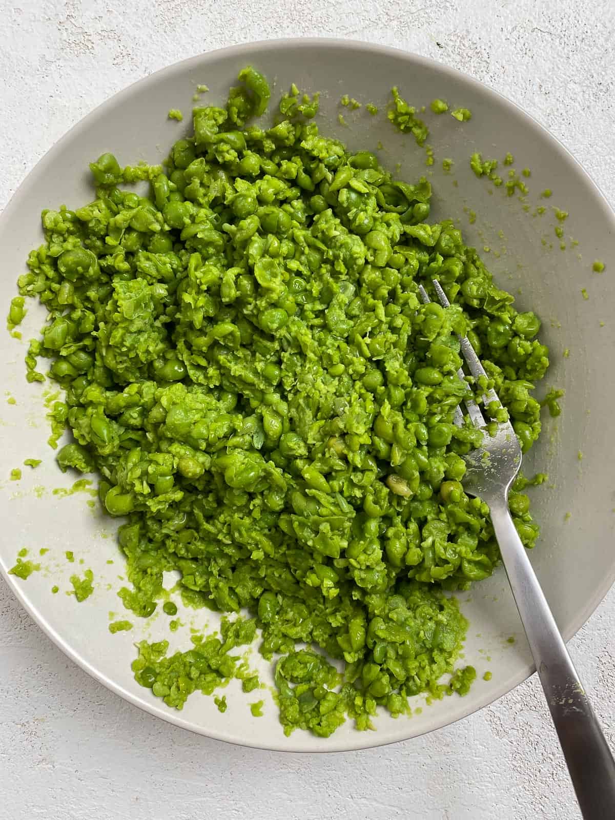 post mashing of peas in a white dish