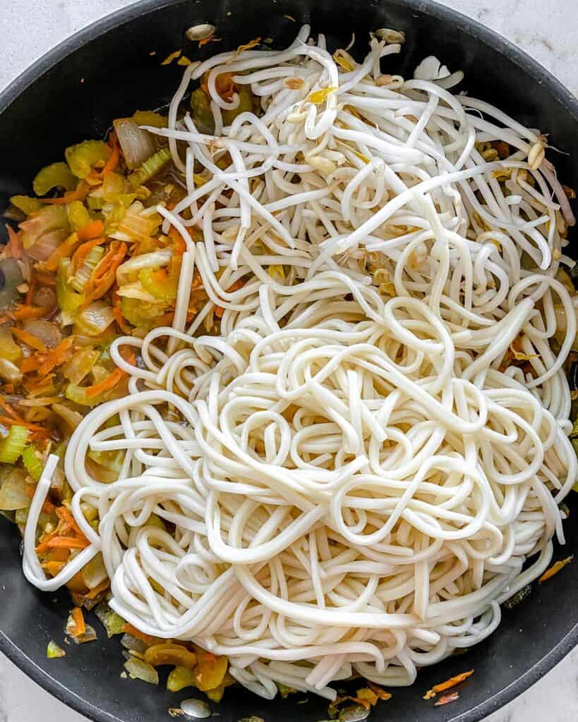 process of adding noodles to pan of veggie chow mein