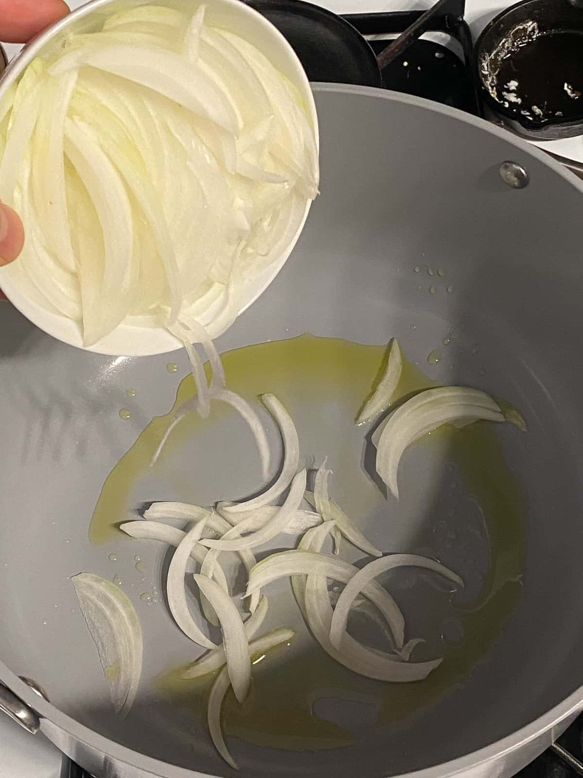 process shot of pouring onions into a pan with oil