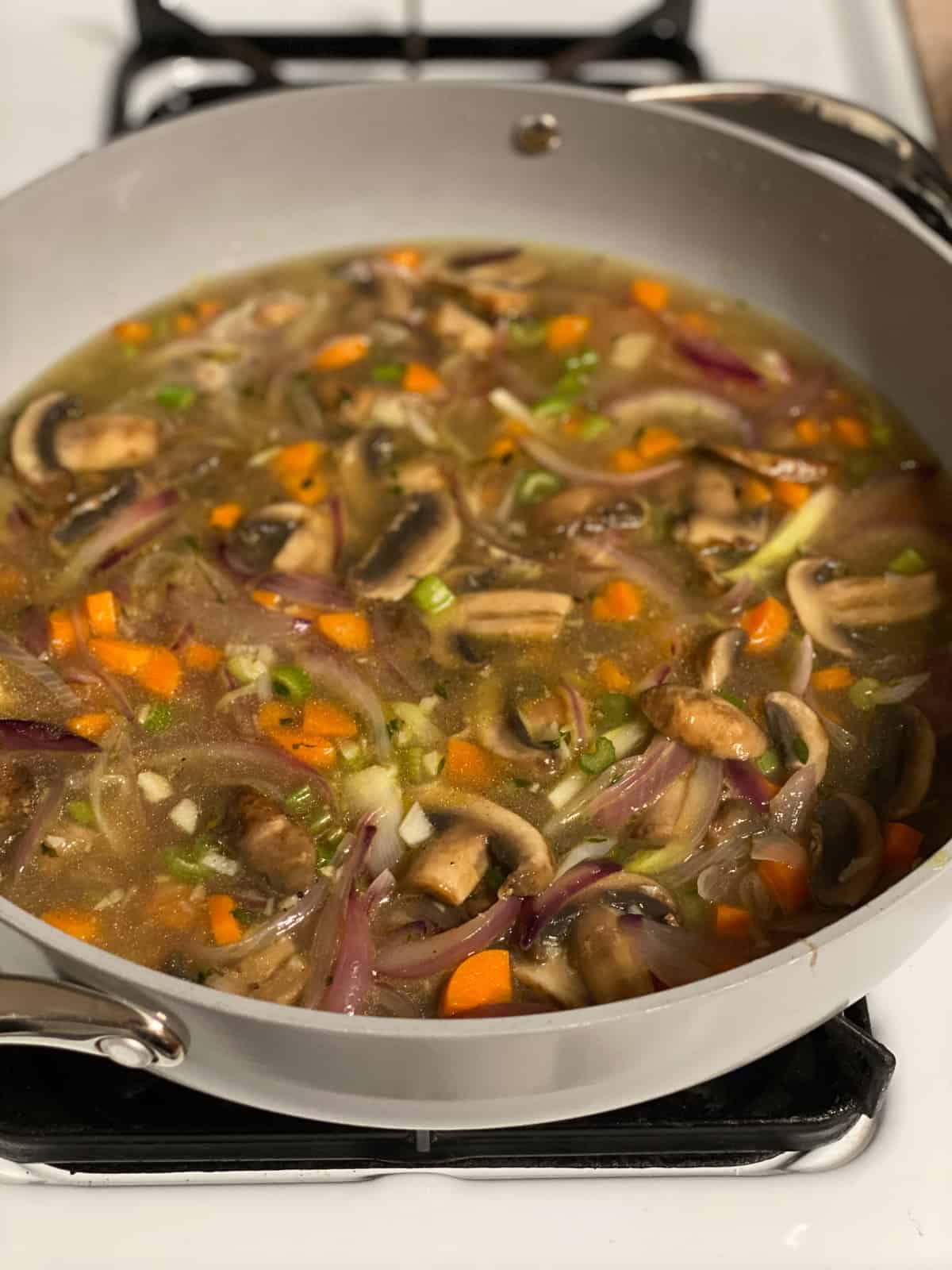 process of cooking veggies with broth in a pan