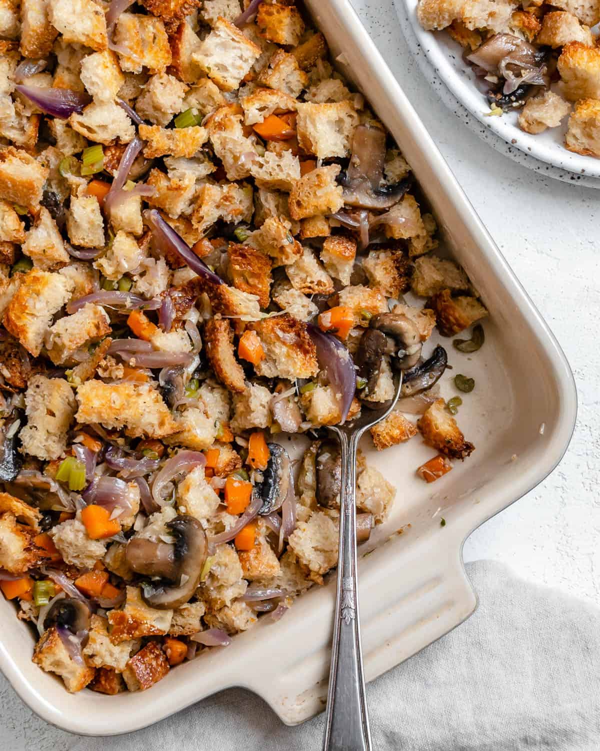 completed Easy Mushroom Stuffing Recipe in dish alongside a plated serving