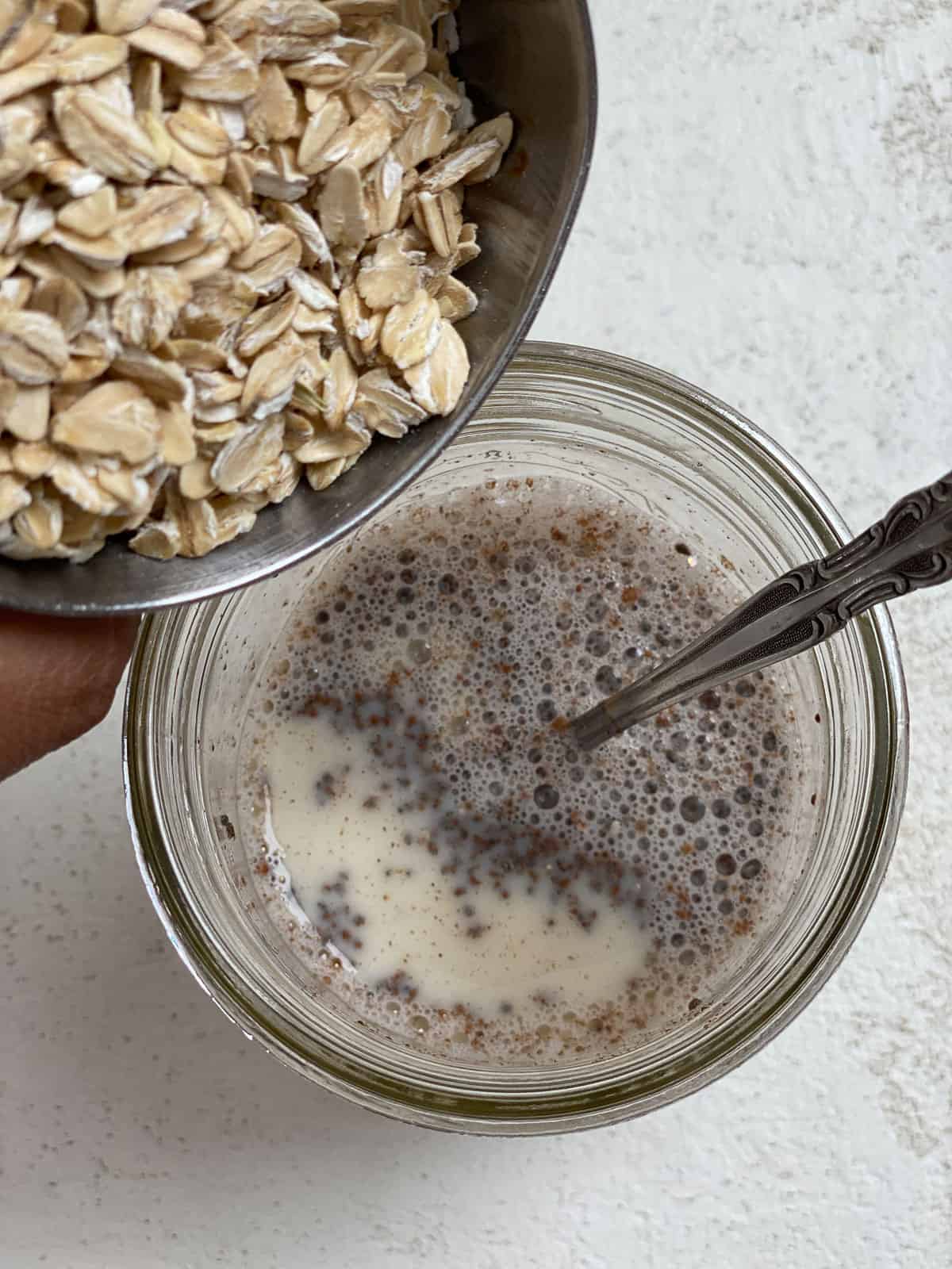 process shot of adding oats to Salted Caramel Overnight Oats in a glass jar