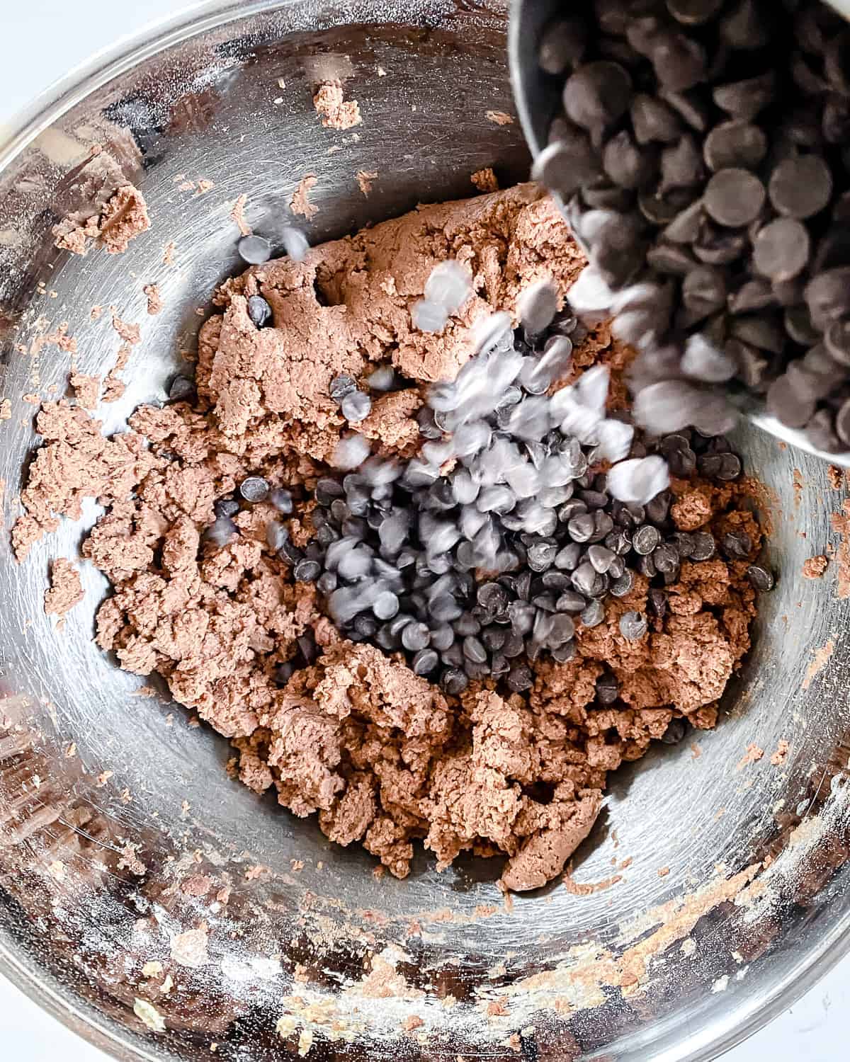 vegan chocolate chips being poured into chocolate peppermint cookie dough