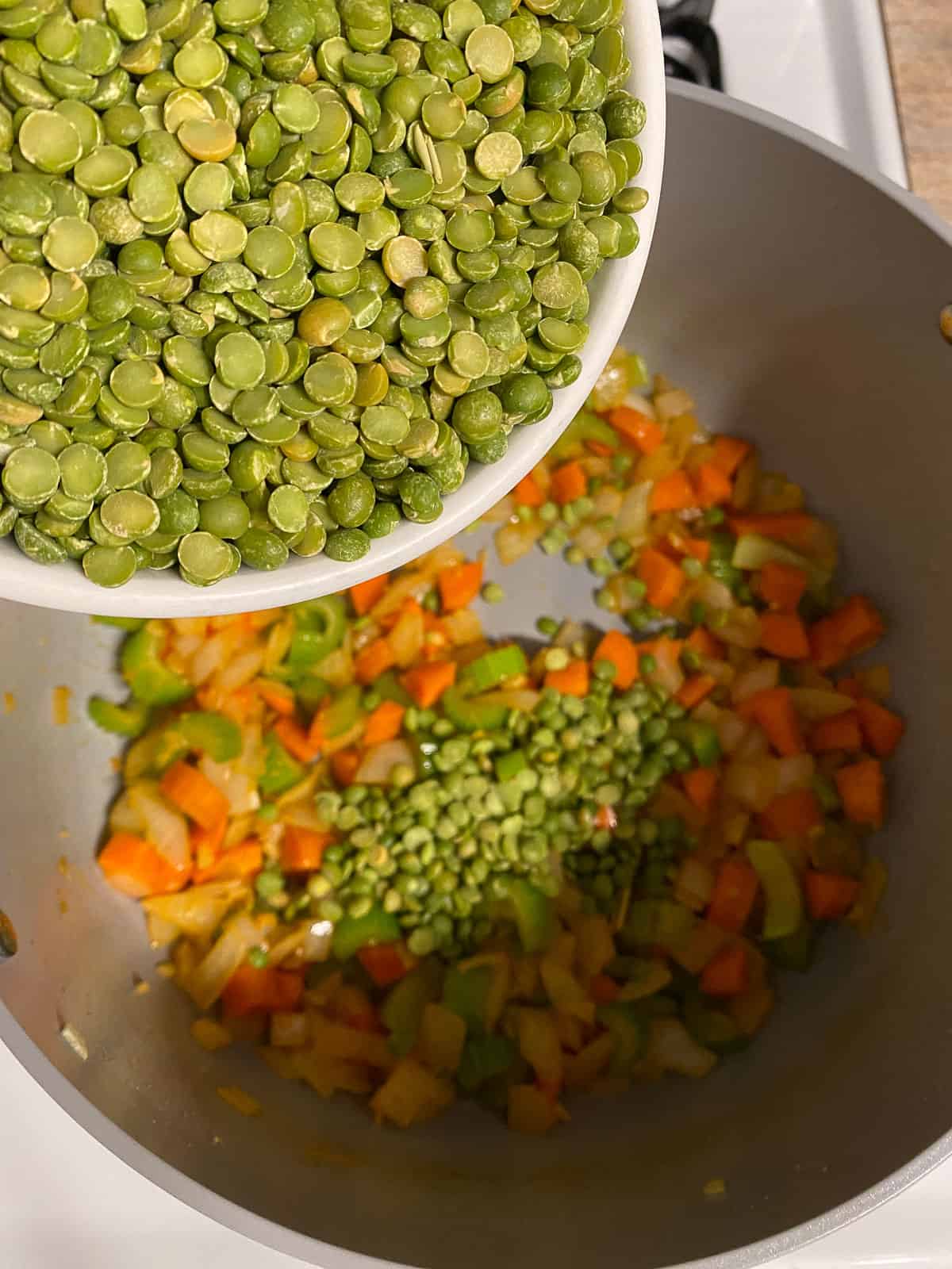 cups of split peas being added to bowl of veggies