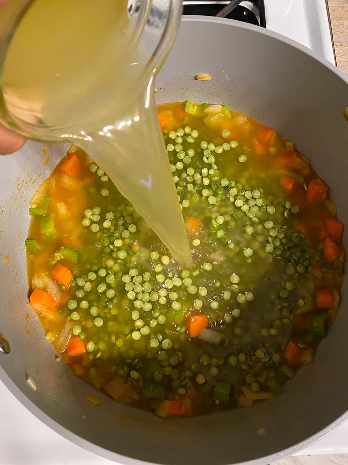 process shot of veggie broth being added to bowl of veggies