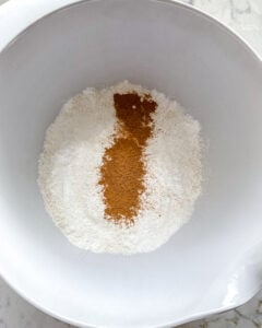 process of adding dry ingredients to white bowl 