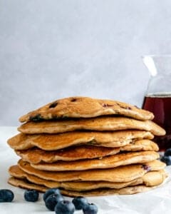 completed stack of blueberry pancakes with syrup in the background
