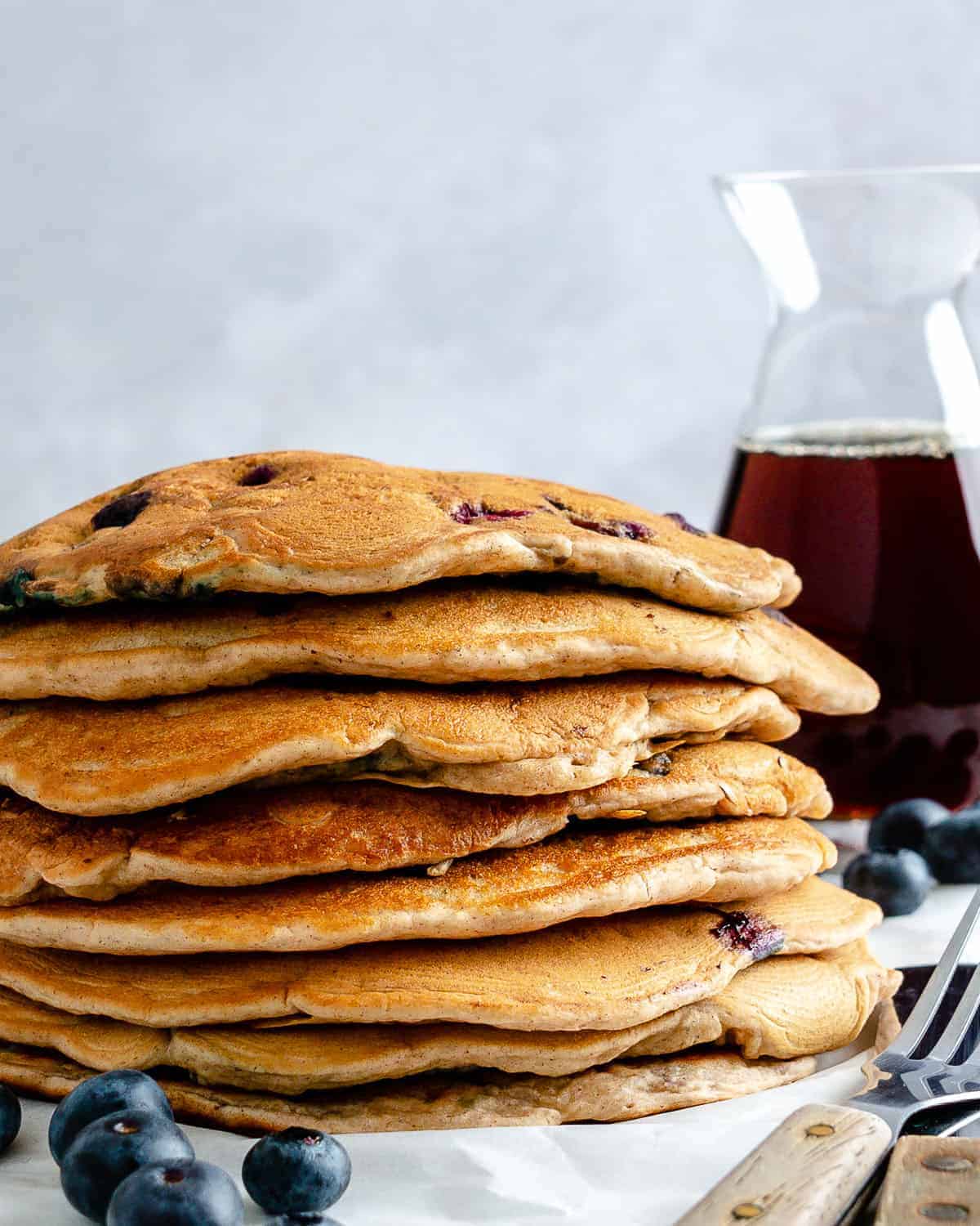 completed stack of blueberry pancakes with syrup in the background