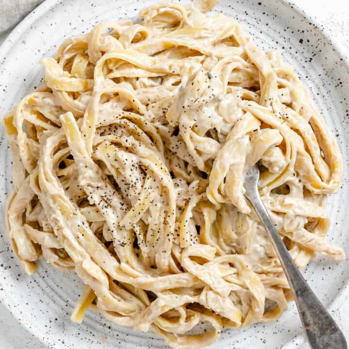 completed Fettuccine Alfredo on a white plate against a white background