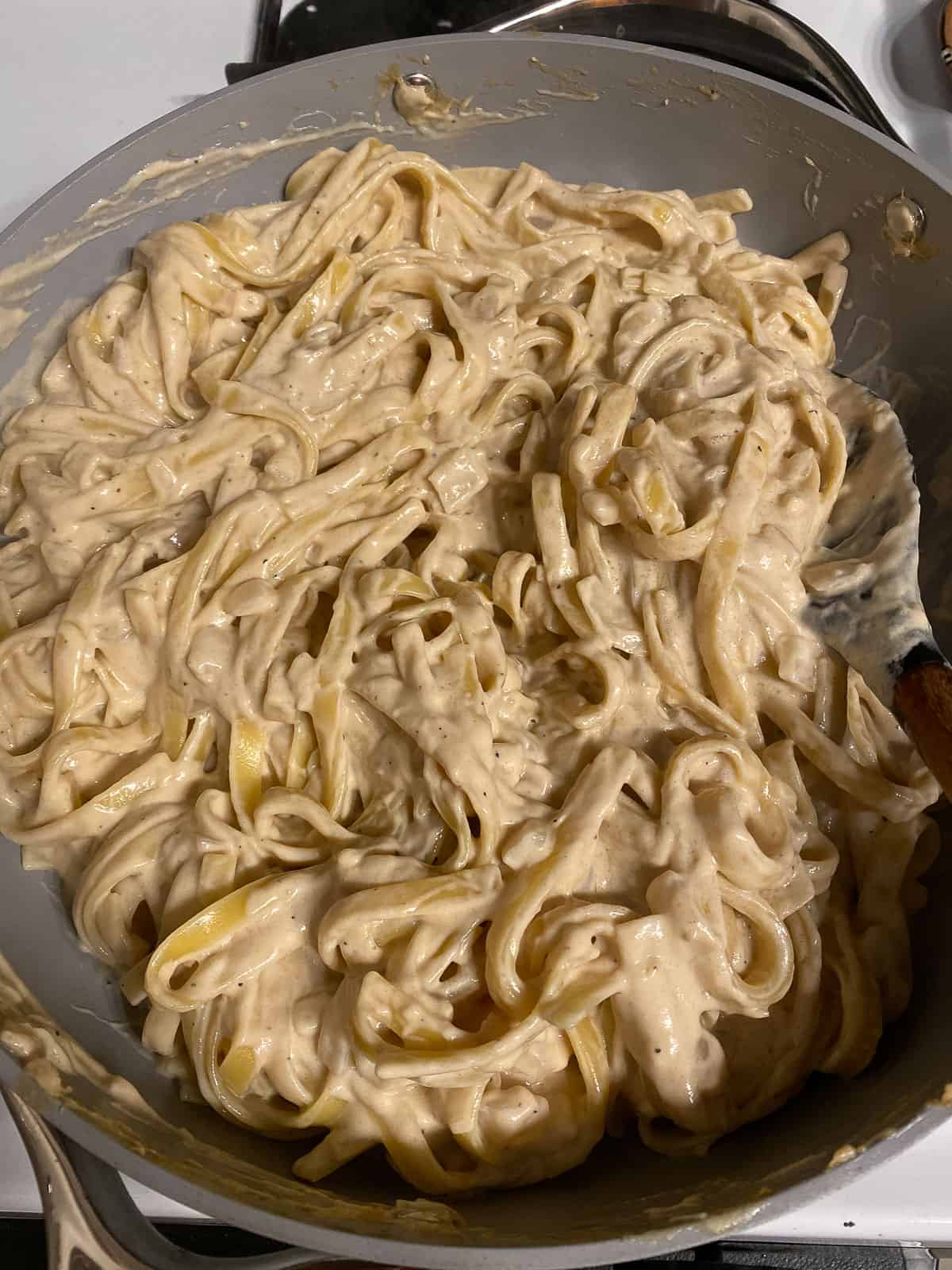 process of mixing stirring fettuccine pasta in pan