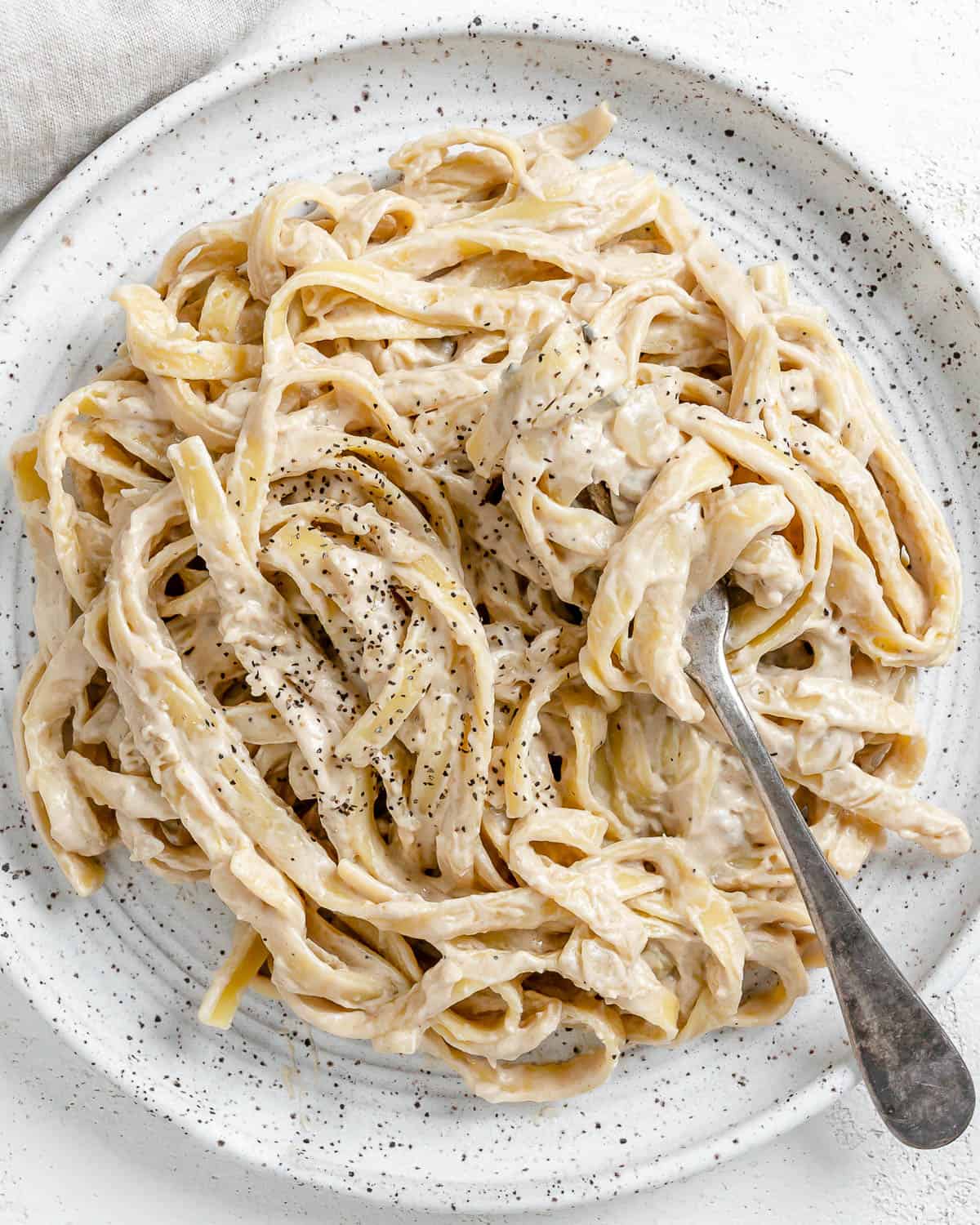 completed Fettuccine Alfredo on a white plate against a white background