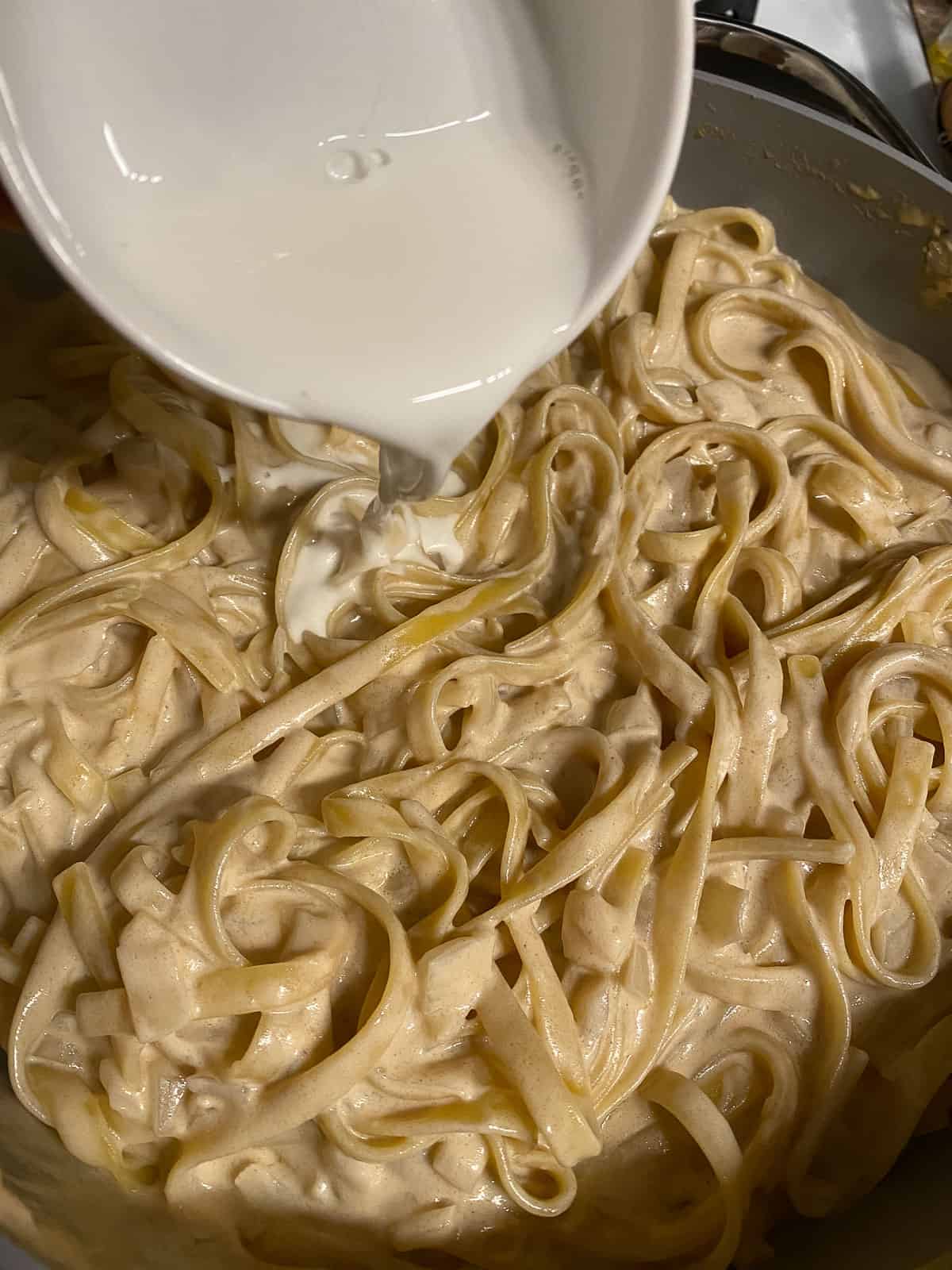 process of adding cornstarch and water to pan of pasta
