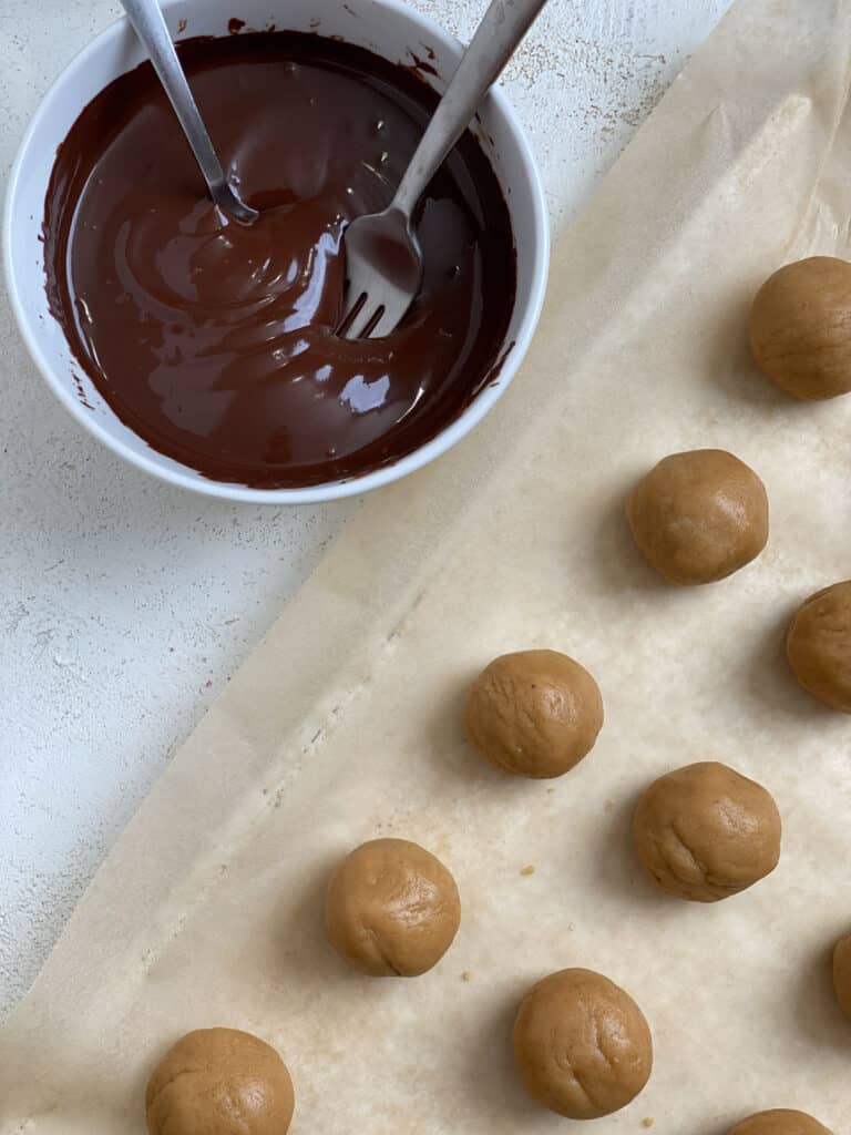 shaped cookie dough balls alongside bowl of melted vegan chocolate