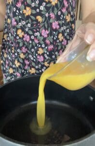 process of pouring orange juice into pot