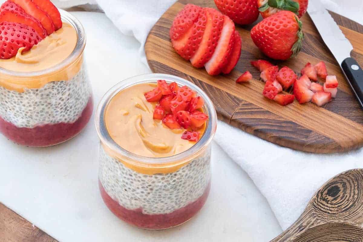 completed Healthy Chia Pudding in a glass jar with strawberries in the background