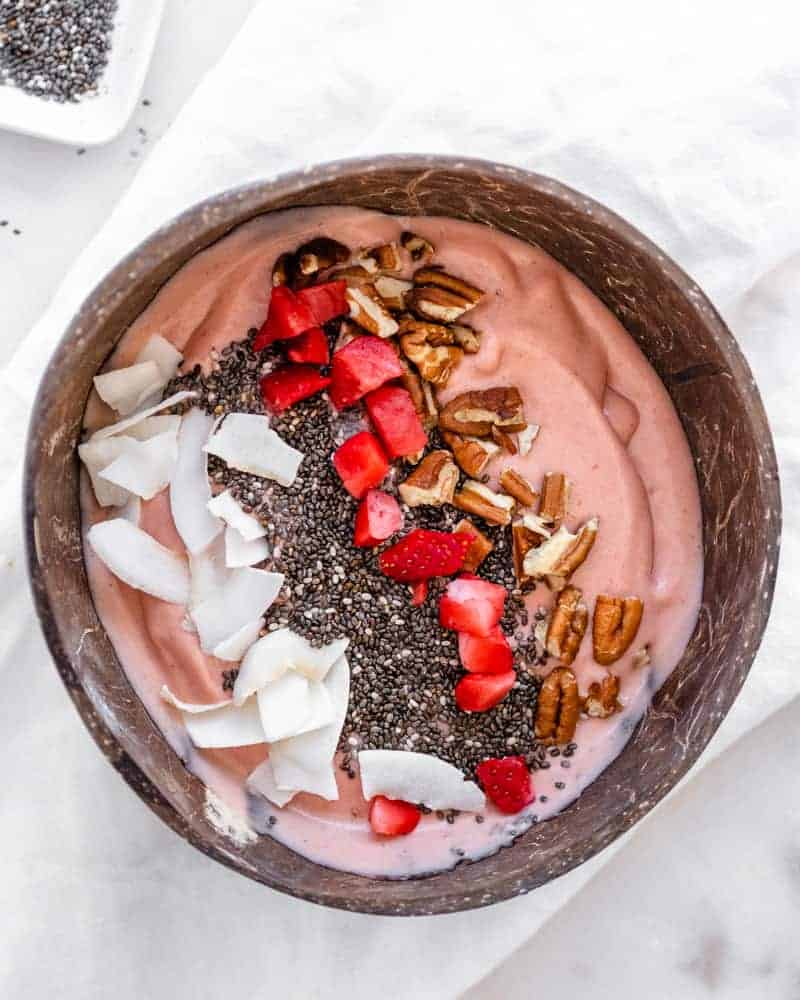 pb&j smoothie bowl in a brown coconut bowl against a white background