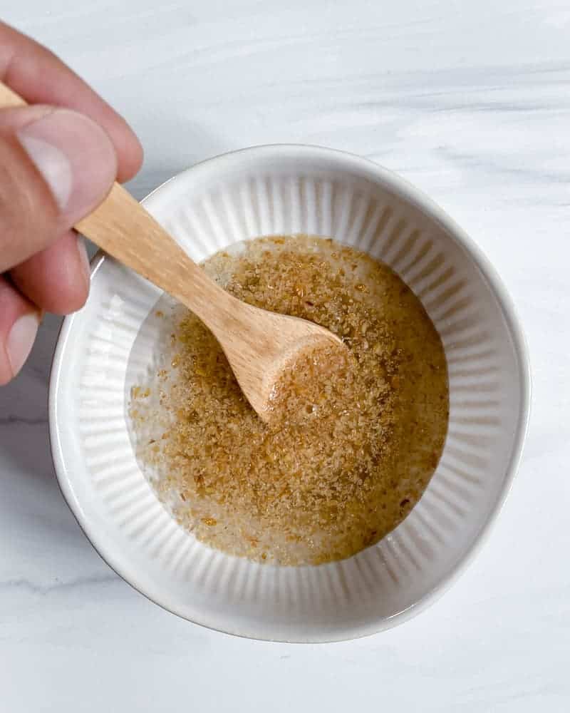process of flaxseed egg being mixed in a small white bowl against white marble surface