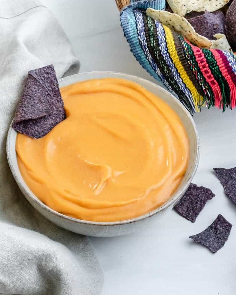 completed nacho cheese with a blue tortilla chip dipped in bowl