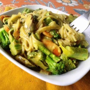 Coco Nut Butter pasta with veggies and a fork in a square white bowl.