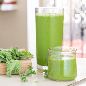 Two glasses of bright green banana kale smoothie on a counter.