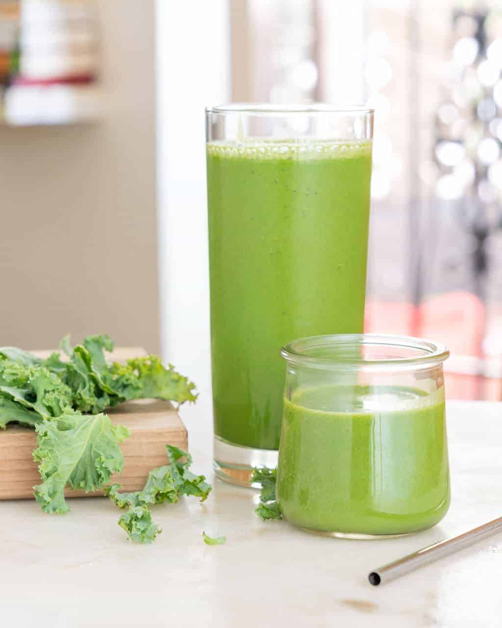 Two glasses of bright green banana kale smoothie on a counter.
