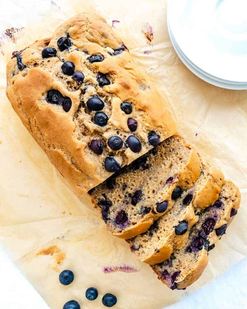 completed Blueberry breakfast loaf with some slices cut on a wood board.