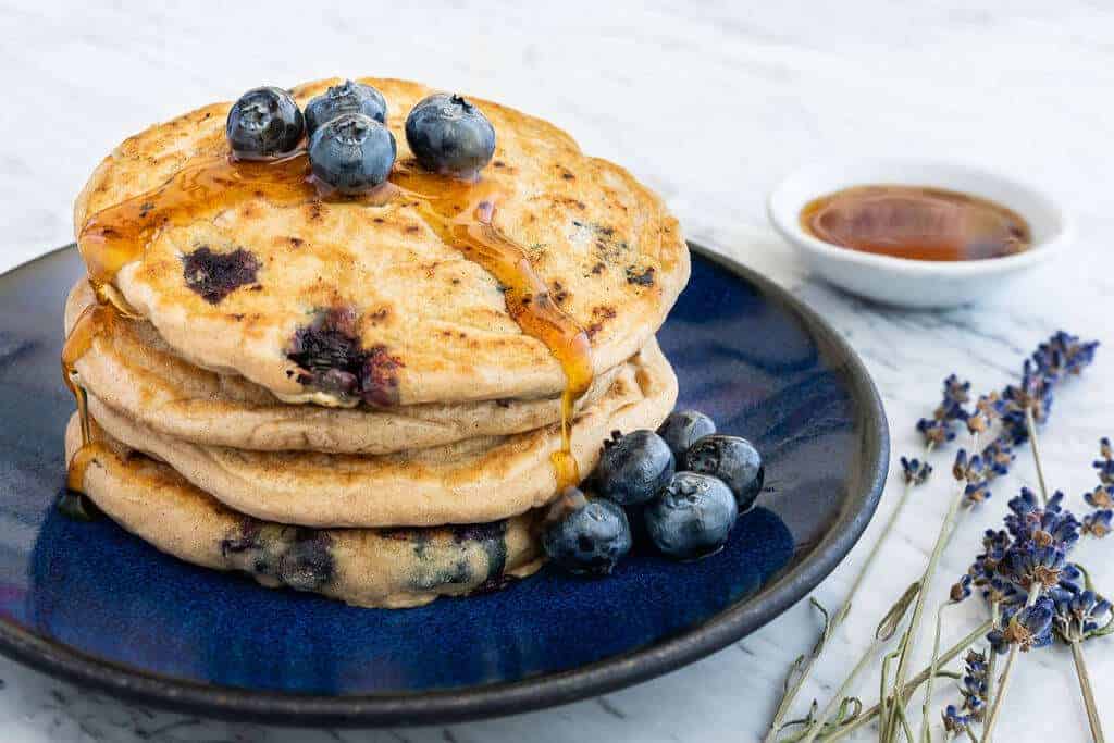 Stack of fresh blueberry pancakes on a blue plate.