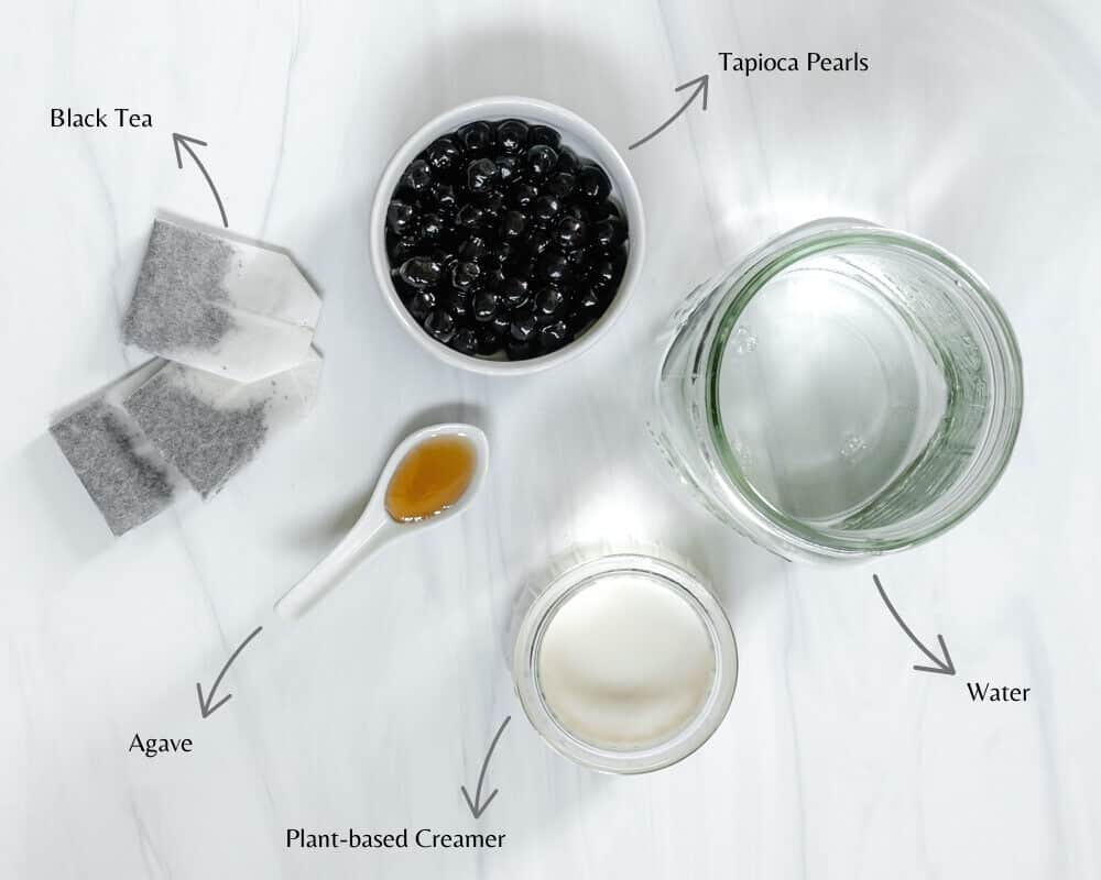 Marble Surface with Tapioca Pearls, Water, Plant-Based Creamer, Black Tea Bags and Agave on top
