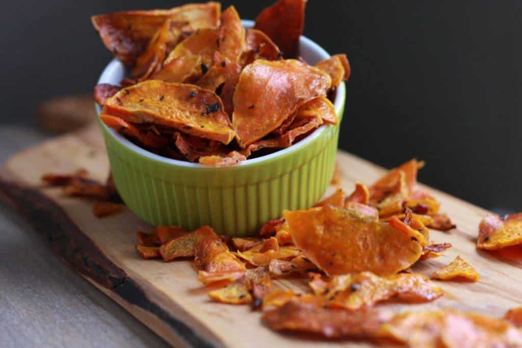 Butternut squash chips in a green bowl on a wood board.