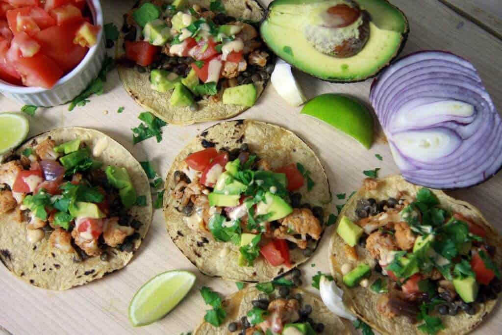 Cauliflower tacos with all the toppings on a wood board.